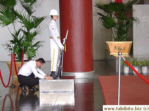 Once he finishes his moves on the step, a staff checks his feet to make sure they are in the exact place and have the right space apart, if not, he pushes the guard's feet for him