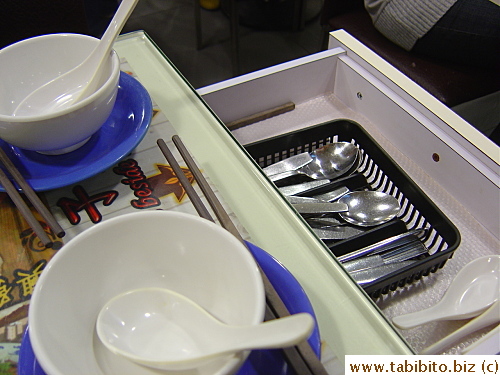 Cutlery is commonly stored in the drawer on the side of the table